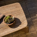 Rectangular patio coffee table with a textured surface, featuring a ceramic bowl of succulents and a book on top