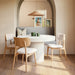Modern interior with white speckled round concrete outdoor dining table and three wooden chairs with white cushions