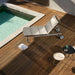 Modern outdoor chaise lounge with metal frame and beige cushions on a wooden deck beside the pool