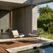 Two patio lounge chairs with beige cushions and teak armrest on a wooden deck patio beside the pool