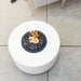 White round fire pit table with lava rocks and flames on a tiled patio floor