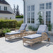 Natural wicker outdoor sunbeds with adjustable backrests, gray cushions and rear wheels on a patio.