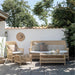 Natural wicker outdoor 3-seater sofa with matching coffee table, armchair and woven stool on a garden patio.