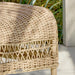 Close-up of a natural wicker outdoor woven stool featuring a light tan finish and open woven base.