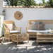 Natural wicker outdoor armchair with white cushions, matching 3-seater sofa, woven stool and coffee table.