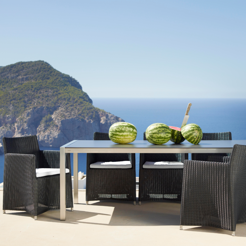 Boxhill's Diamond Terrace Weave Chair lifestyle image with a dining table at seafront and an island in front.
