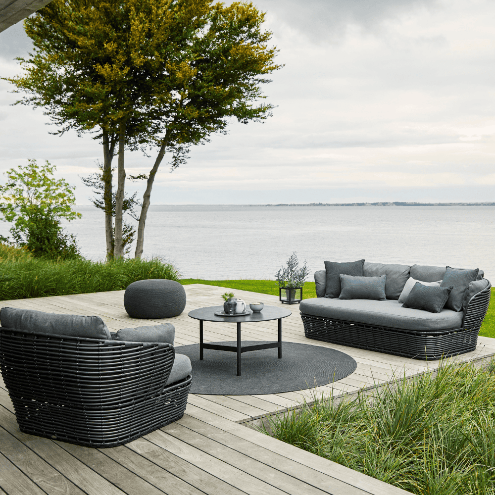 Boxhiil's Discover Round Outdoor Rug Dark Grey lifestyle image with 3-seater sofa, lounge chair and round table at the center