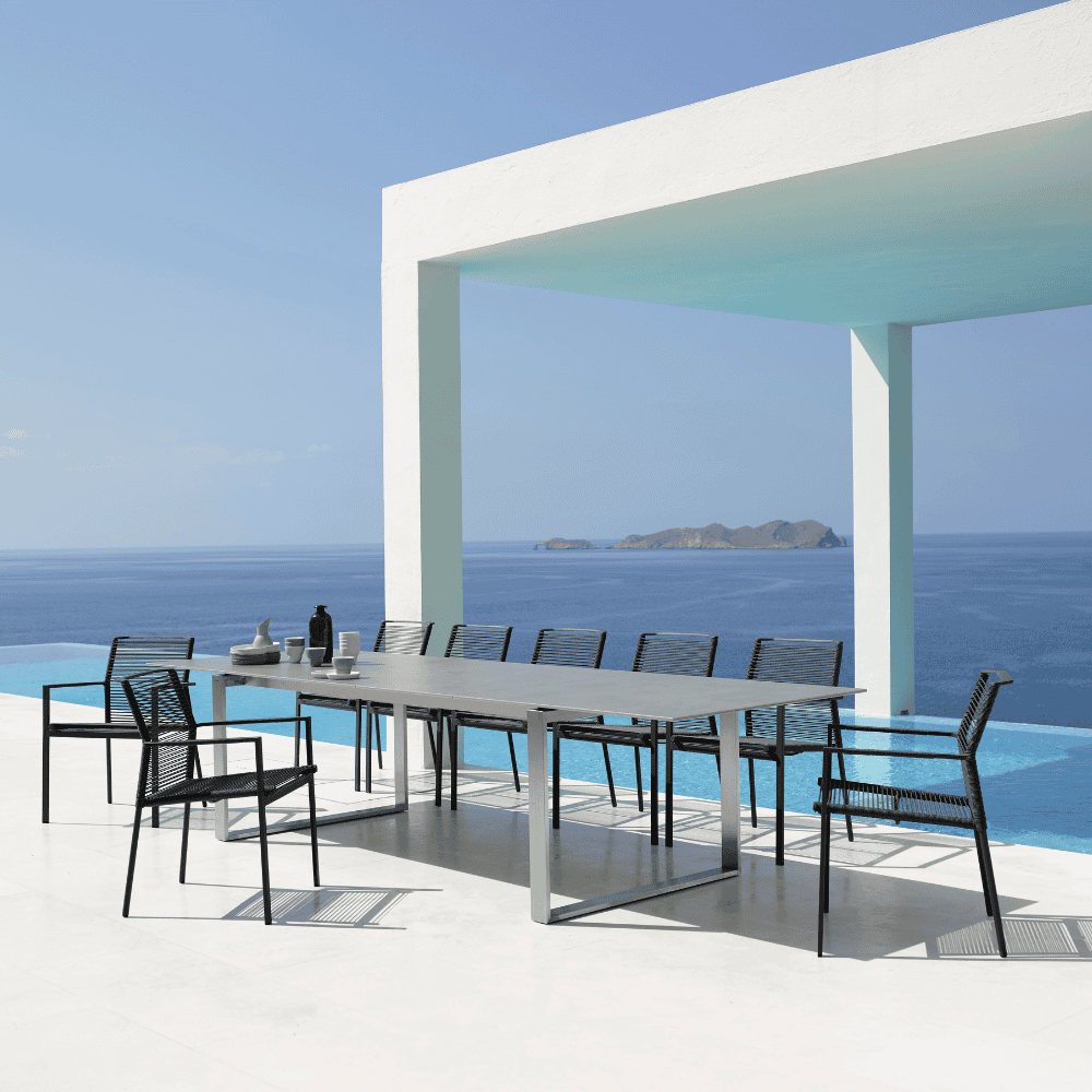 Boxhill's Edge Stackable Outdoor Armchair lifestyle image with long dining table beside the pool