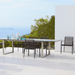 Boxhill's Edge Stackable Outdoor Armchair lifestyle image with long dining table at patio