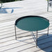 Dark green round metal outdoor tray table placed on a wooden surface in daylight