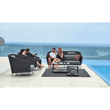 Boxhill's Mega Modern Outdoor 2-Seater Sofa lifestyle image with Mega Modern Outdoor Lounge Chair, 2 Level Coffee Table and 2 couples sitting down having a chat beside the pool