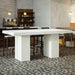 Modern interior setting with white speckled rectangular concrete outdoor bar tables, black high chairs, and pendant globe lights