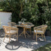 Natural rattan outdoor dining side chairs with a matching round dining table on a garden patio.