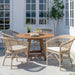 Natural rattan outdoor dining side chairs with white seat cushions around a round wooden dining table.