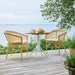 Natural rattan outdoor dining side chairs around a matching white pedestal table on a wooden deck.