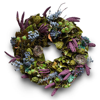 Festive wreath with natural accents of green leaves, purple flowers, and small  nests on a white background.