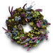 Festive wreath with natural accents of green leaves, purple flowers, and small  nests on a white background