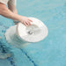 Person’s hands holding white in-pool side table while dipping it into pool water.