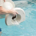Hands draining water from a white in-pool side table in a swimming pool.
