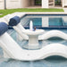 Two white in-pool chaise loungers with dark blue headrests and a round side table on a sunshelf.