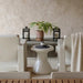 Minimalist seating area with white chairs, small round patio side table with cup, potted plant, and two black lanterns on bench.