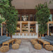 Natural wicker outdoor ottomans with matching wooden coffee tables and gray sofas in a lounge setting.