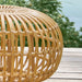 Close-up of a natural wicker outdoor ottoman featuring a light tan finish and open woven frame.