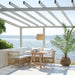 Natural wooden outdoor dining table with matching rattan seating on a seaside terrace beneath a white pergola.
