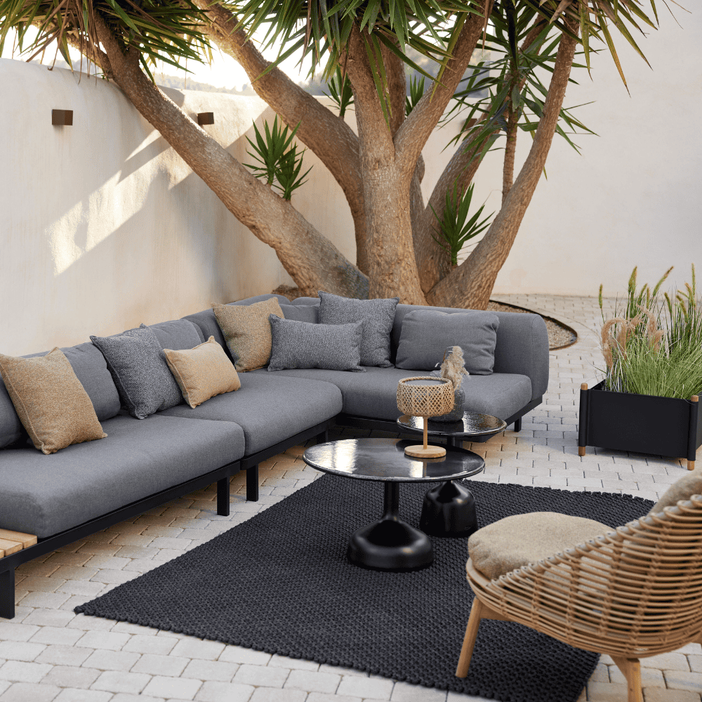 Boxhill's Glaze Outdoor Round Coffee Table lifestyle image with module sofa beside the tree at patio