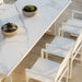 A white ceramic table top surrounded by matching white chairs in a modern setting.
