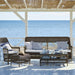 Grey wicker outdoor glass-top coffee table with matching seating featuring blue and white striped cushions.