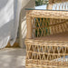 A close-up of a woven rattan coffee table with a glass top, showcasing its intricate design and natural color.