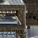 Close-up of a grey wicker outdoor glass-top coffee table with stacked books on the lower shelf.