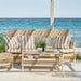 Natural wicker outdoor glass-top coffee table with matching sofa featuring beige and white striped cushions.