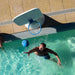 A man in a swimming pool plays with a blue basketball near a white poolside basketball hoop.