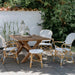 Wicker outdoor dining chairs with woven wicker seat and back beside a matching square wooden dining table.