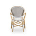 Rear view of a natural rattan outdoor dining armchair with a beige and white striped woven back.