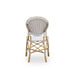 Rear view of a natural rattan outdoor dining side chair with a cappuccino and white patterned woven back.