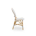 Side view of a natural rattan outdoor dining side chair with a cappuccino and white patterned woven back.