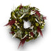 Festive wreath with green magnolia leaves, white leaves, red accents, and delicate dried flowers on a white background.