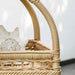 Close-up of a natural wicker outdoor bar cart featuring an open woven basket shelf.