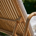 Close-up of a natural rattan outdoor sun lounger featuring a woven backrest, armrest and white cushion.