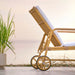 Natural rattan outdoor sun lounger featuring white cushions and rear wheels viewed from the side.