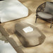 Patio seating area with a modern concrete outdoor coffee table, white cushioned seats, and a woven chair on a tiled floor
