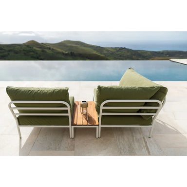 Outdoor sectional sofa with olive green cushions and white metal frame, paired with a wooden side table beside the pool, overlooking green hills