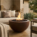 Outdoor patio with round concrete fire pit, seating area, and natural elements