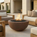 Round concrete Fire pit in a patio setting with outdoor furniture and a building in the background
