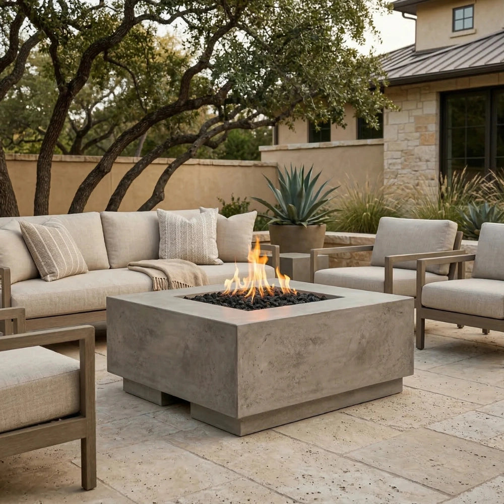 Outdoor patio with grey square concrete fire pit, seating area, and garden elements.