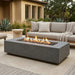 Outdoor patio with a grey rectangular concrete fire pit table and seating area.