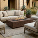 Outdoor patio with beige sectional sofa, rectangular concrete fire pit table, and potted plants.